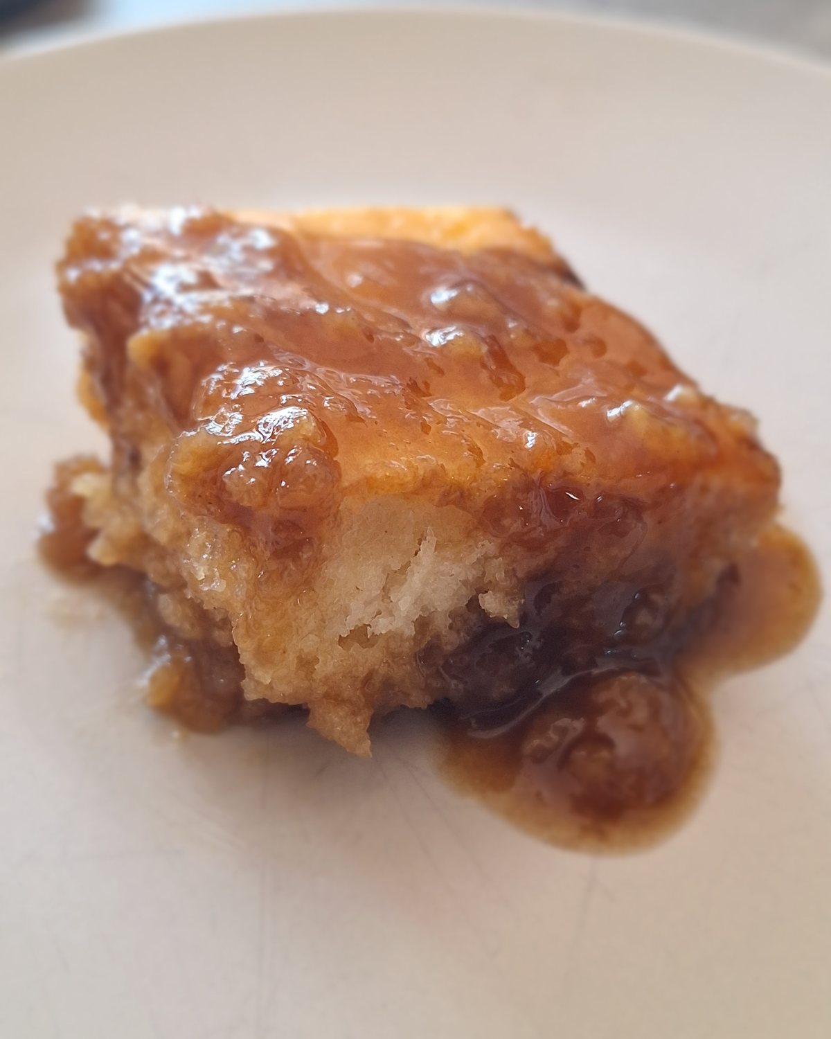 A square of pouding chômeur under warm caramel sauce